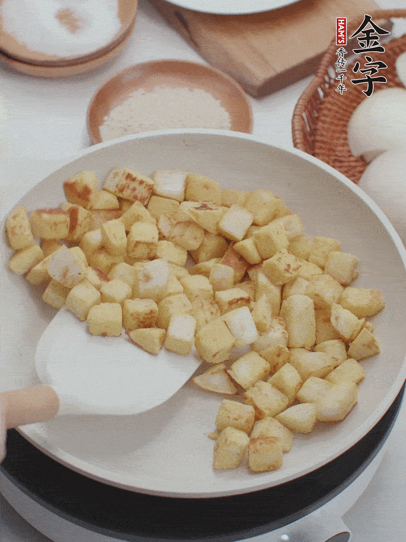 起鍋熱油，倒入饅頭丁，小火煎至蛋液凝固定型再翻面，饅頭丁部煎至金黃時(shí)盛起待用。