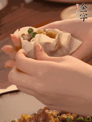 取一大勺餡料放進(jìn)餃子皮里，用大拇指按住頂部餡料，再用虎口掐出形狀。